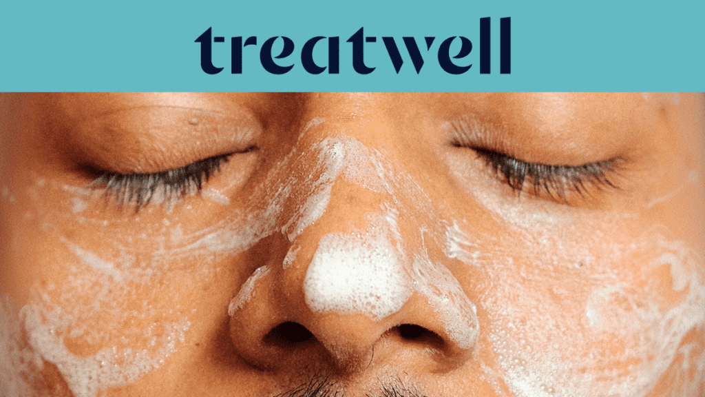 Primer plano do rosto de uma pessoa de olhos fechados, coberto por um produto de limpeza facial espumoso branco. No topo, uma faixa azul-claro mostra o logótipo da "Treatwell" em azul-escuro.