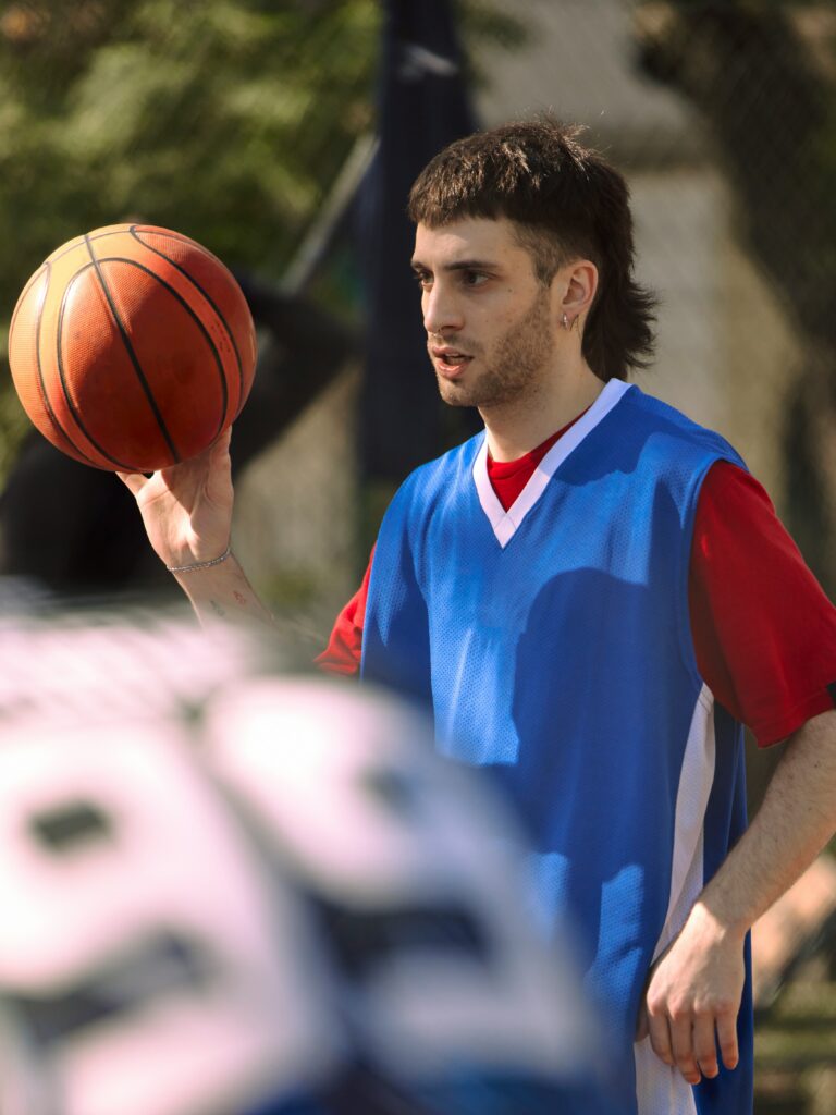 [ALT_TEXT: A young man with a fade mullet haircut playing basketball.]