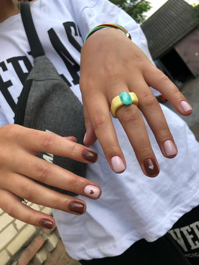 mulher de t-shirt branca a mostrar a manicure BIAB à cmara no exterior