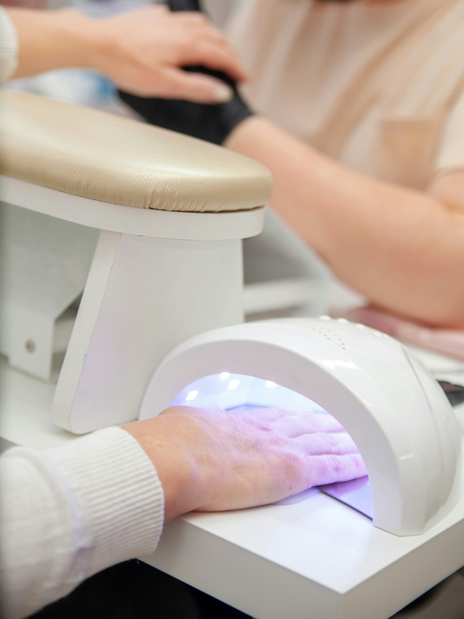 Cliente num salão de unhas a curar a manicure BIAB sob lmpada UV