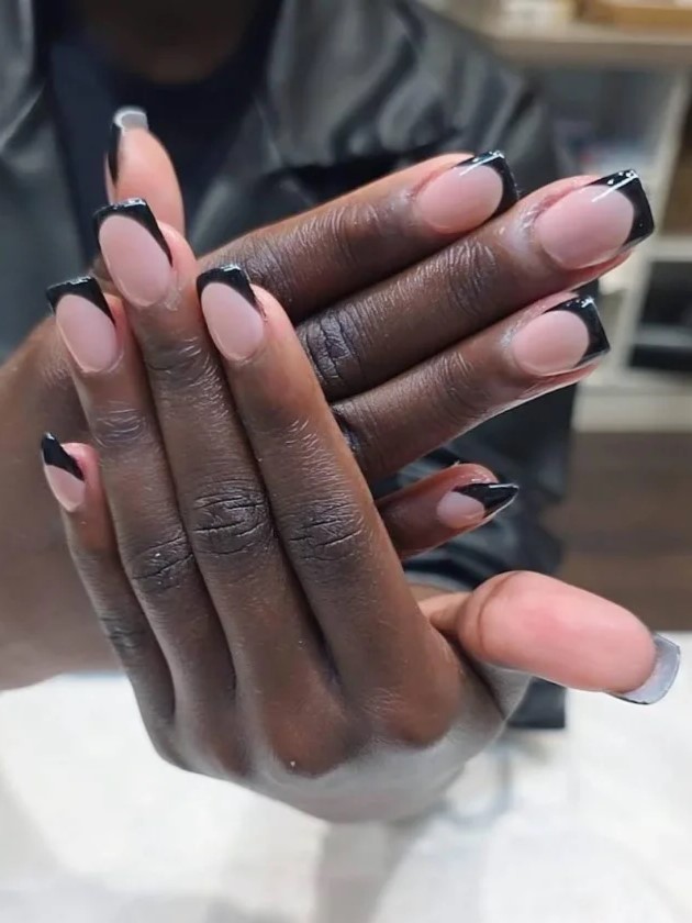 mulher num salo de unhas a mostrar à cmara uma manicure BIAB nude com extenses pretas