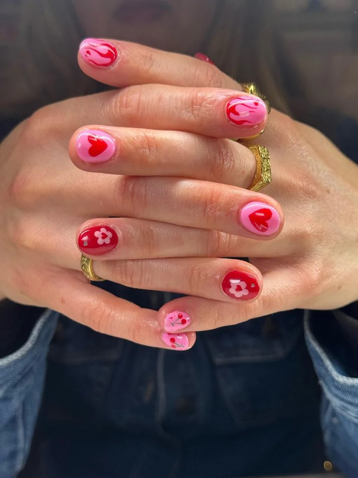 mos de uma mulher juntas com uma manicure BIAB rosa e vermelha viva com nail art