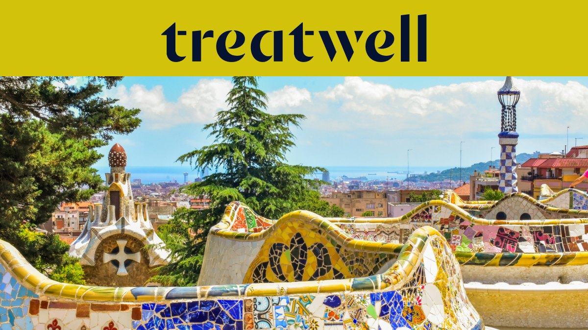 Uma vista panormica de Barcelona a partir do Parque Güell, apresentando os icónicos bancos de mosaico coloridos de Antoni Gaudí e as torres de estilo de conto de fadas em primeiro plano, com a cidade e o mar ao fundo. Um banner amarelo no topo exibe o logótipo "treatwell".