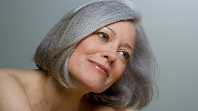 Plano aproximado de uma mulher com um bob grisalho liso e maquilhagem natural