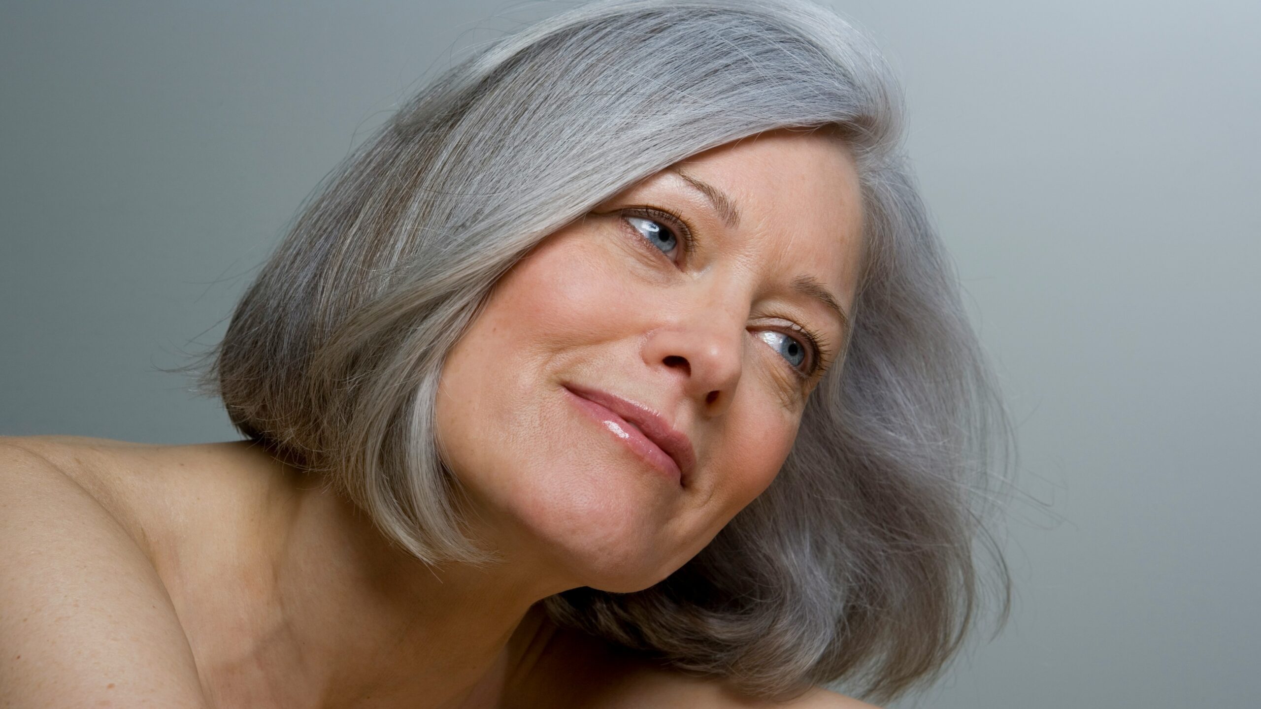 Plano aproximado de uma mulher com um bob grisalho liso e maquilhagem natural