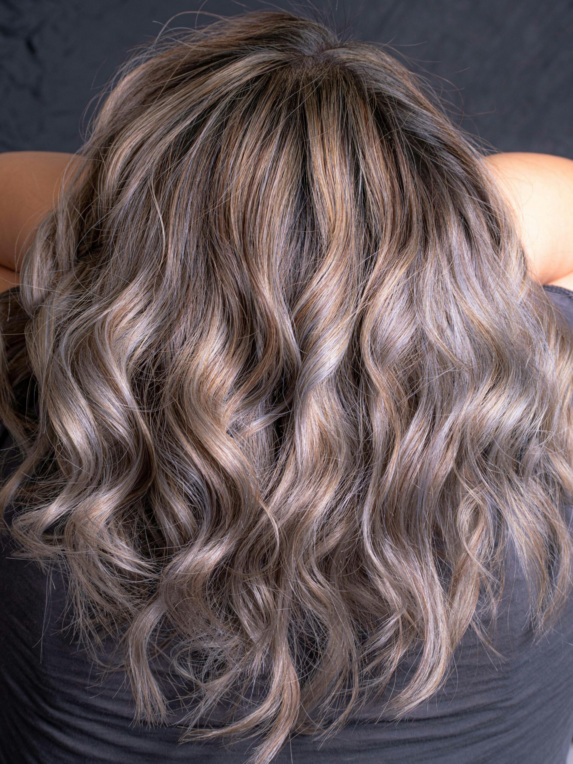 Parte de trás da cabeça de uma mulher com cabelo ondulado grisalho disfarçado