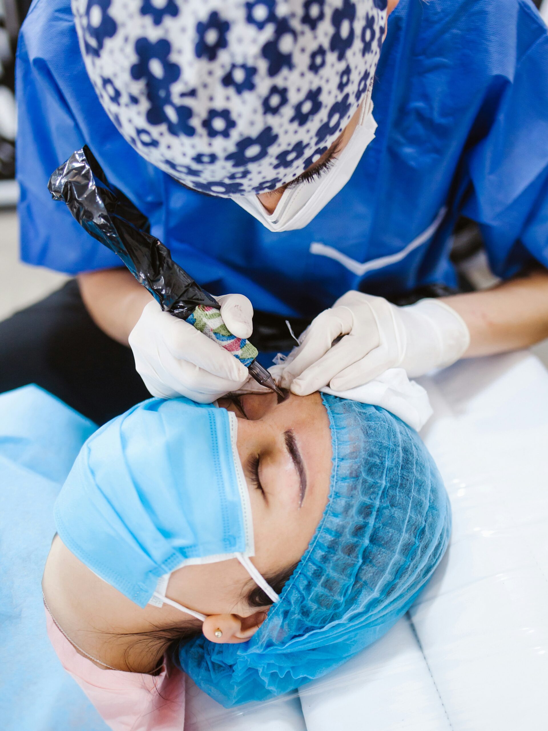 Close-up de uma mulher a receber um tratamento de microblading de uma técnica, deitada numa cama de tratamento e a usar uma máscara