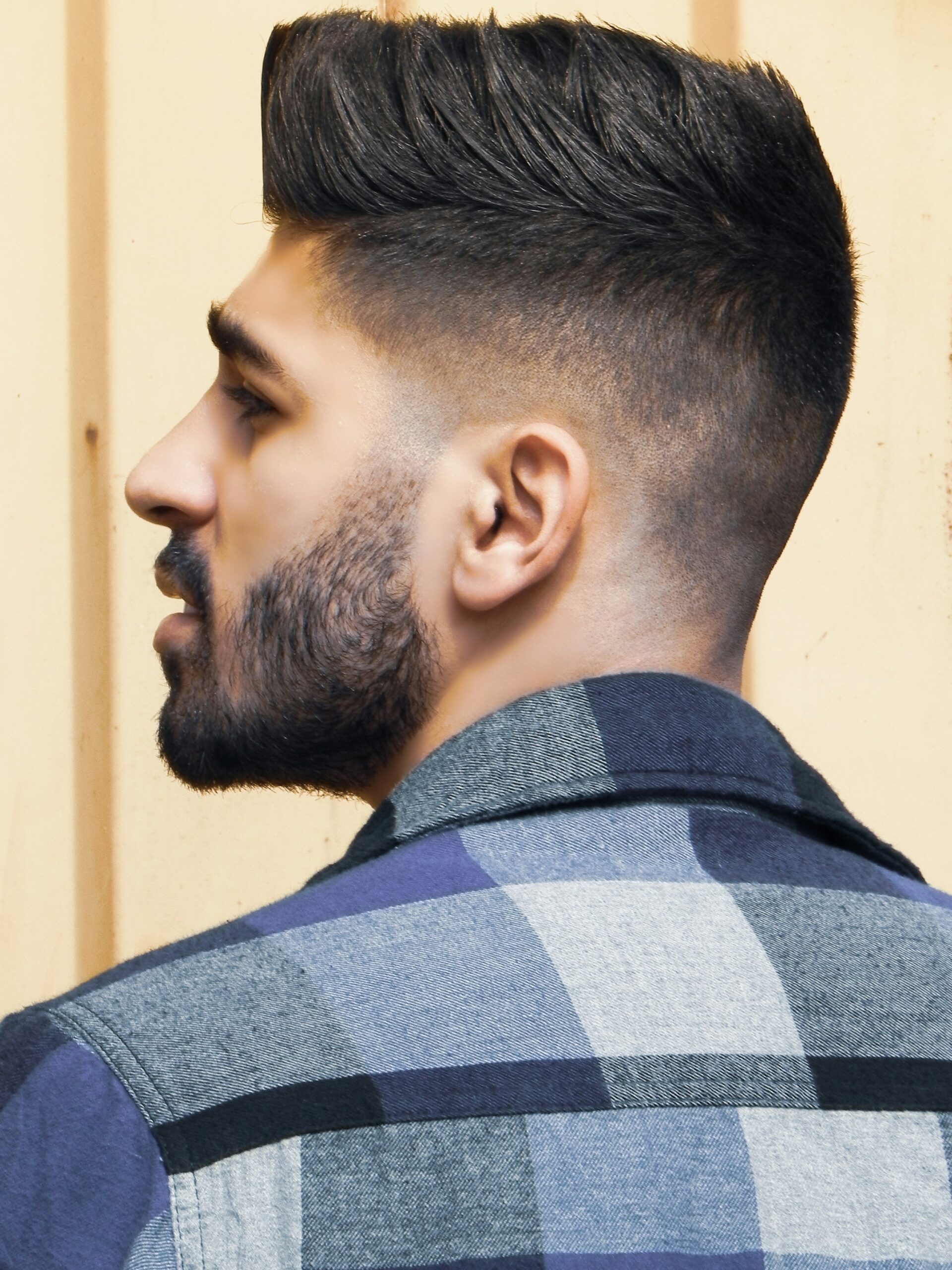 Retrato de perfil de um homem com penteado faux hawk combinado com um taper fade alto