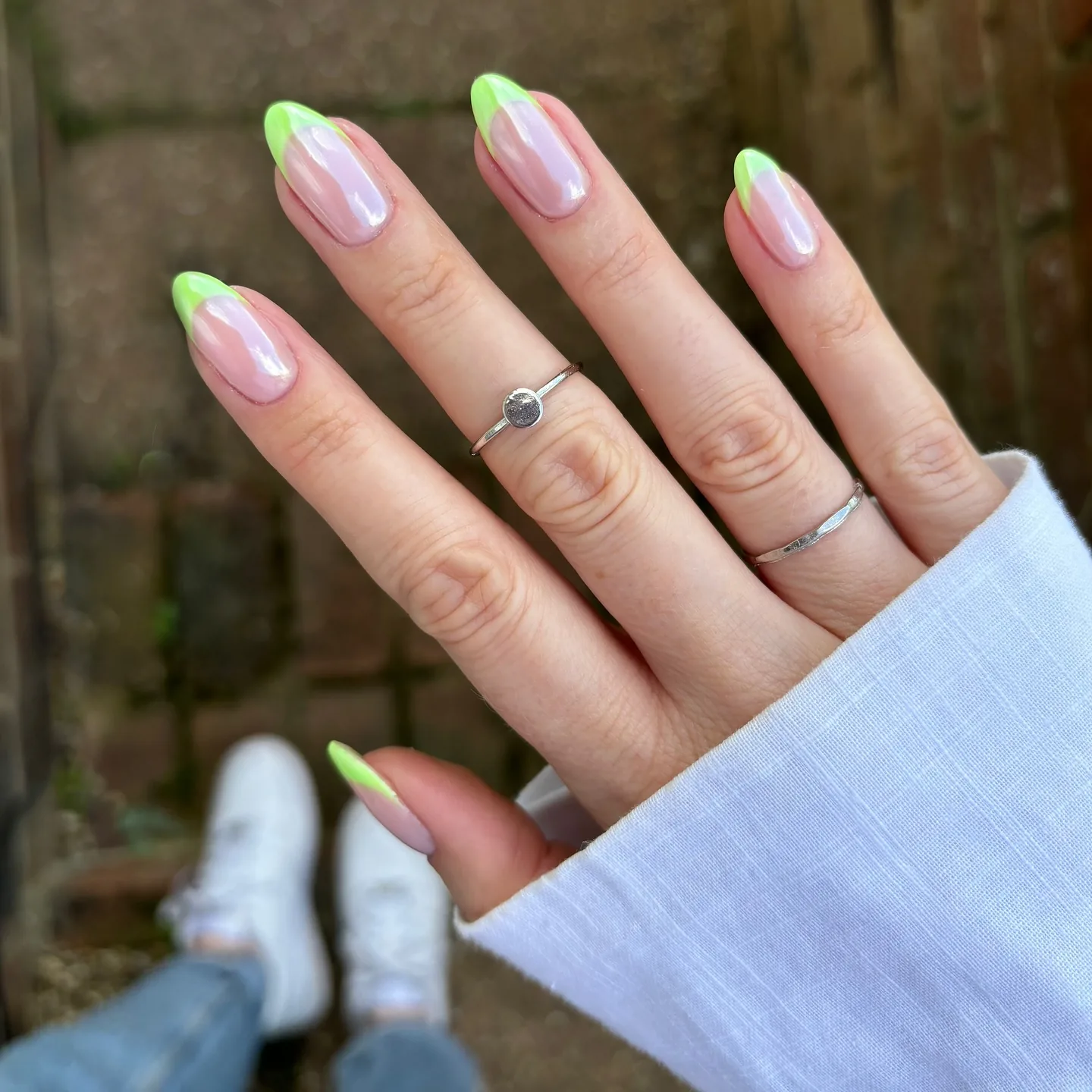 Unhas em formato amêndoa com pontas francesas verde-lima sobre uma base cromada perolada e glaceada.