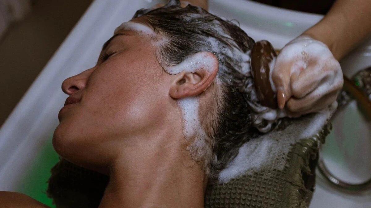 Grande plano de um terapeuta a fazer um head spa japonês com uma escova de couro cabeludo numa cliente