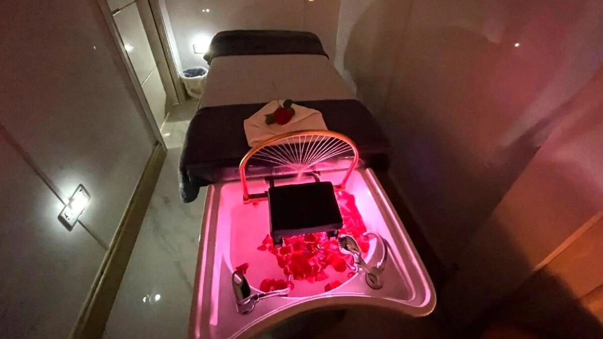 Interior de uma sala de head spa japonês acolhedora com luz suave, com uma marquesa, um lavatório com pétalas e equipamento de spa
