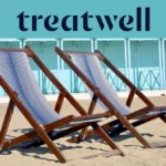 Duas espreguiçadeiras de madeira às riscas na areia em frente a cabanas de praia azul-pastel na costa da Versilia