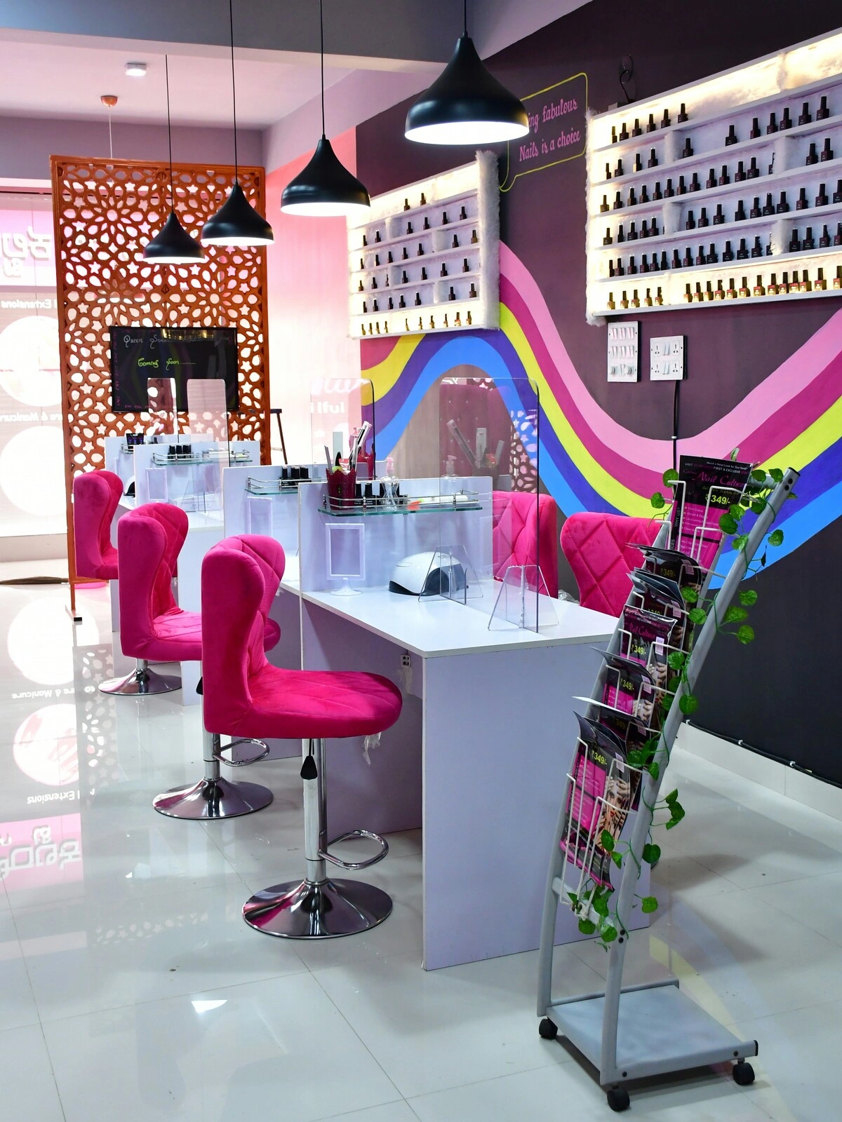 Interior de um salão de unhas com secretárias brancas limpas e arrumadas, cadeiras de veludo cor-de-rosa e uma parede roxa