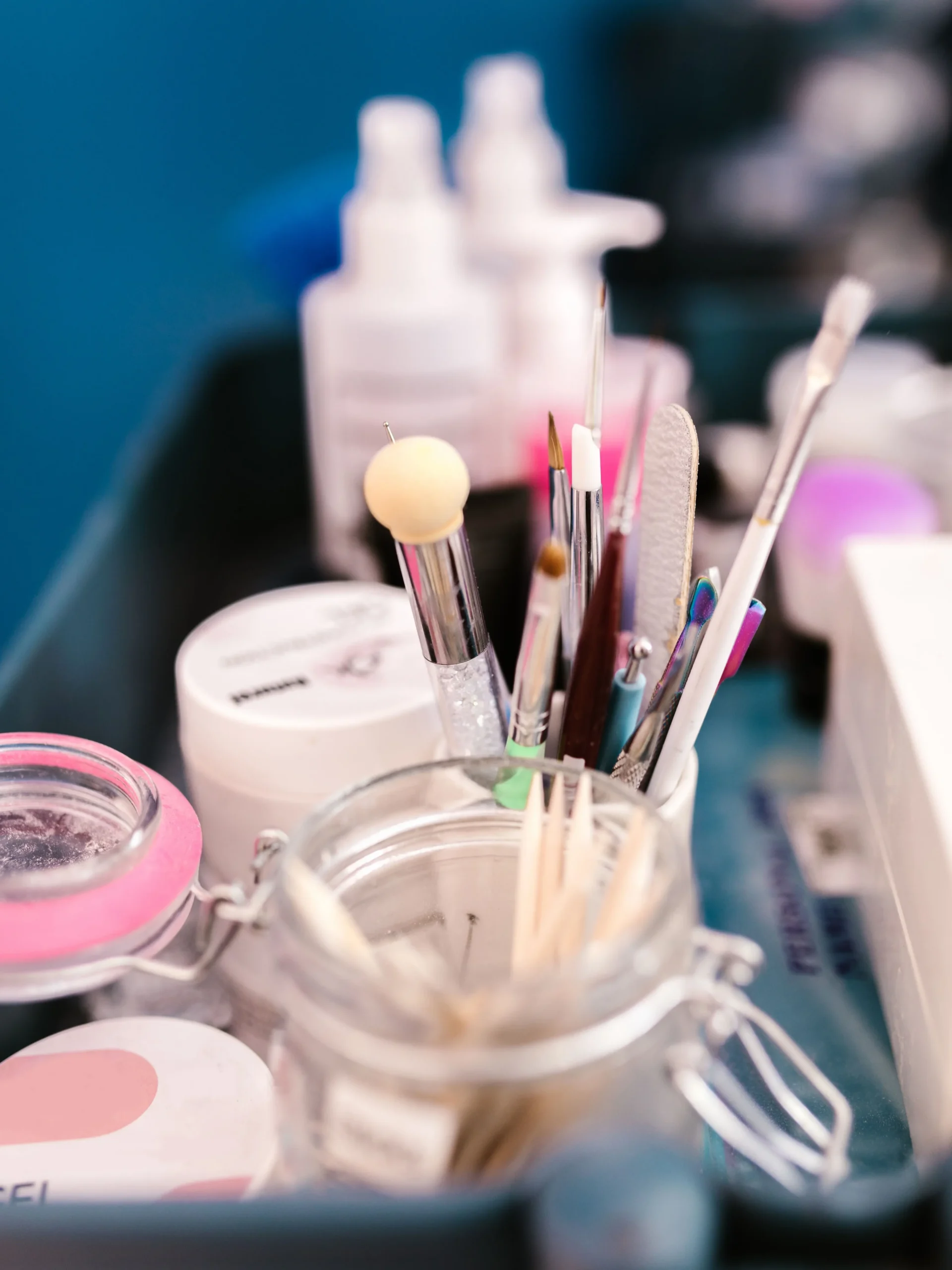 Grande plano da bancada de trabalho de uma profissional de unhas num salão, com ferramentas de manicure, pincéis e produtos