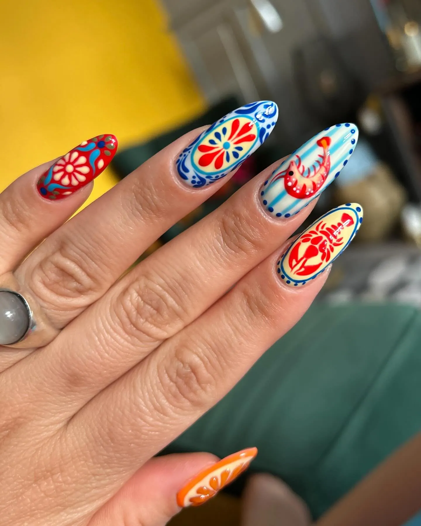 Nail art Mani em modo viagem em unhas de formato amendoado, com motivos de inspiração mediterrânica em vermelho, azul e laranja