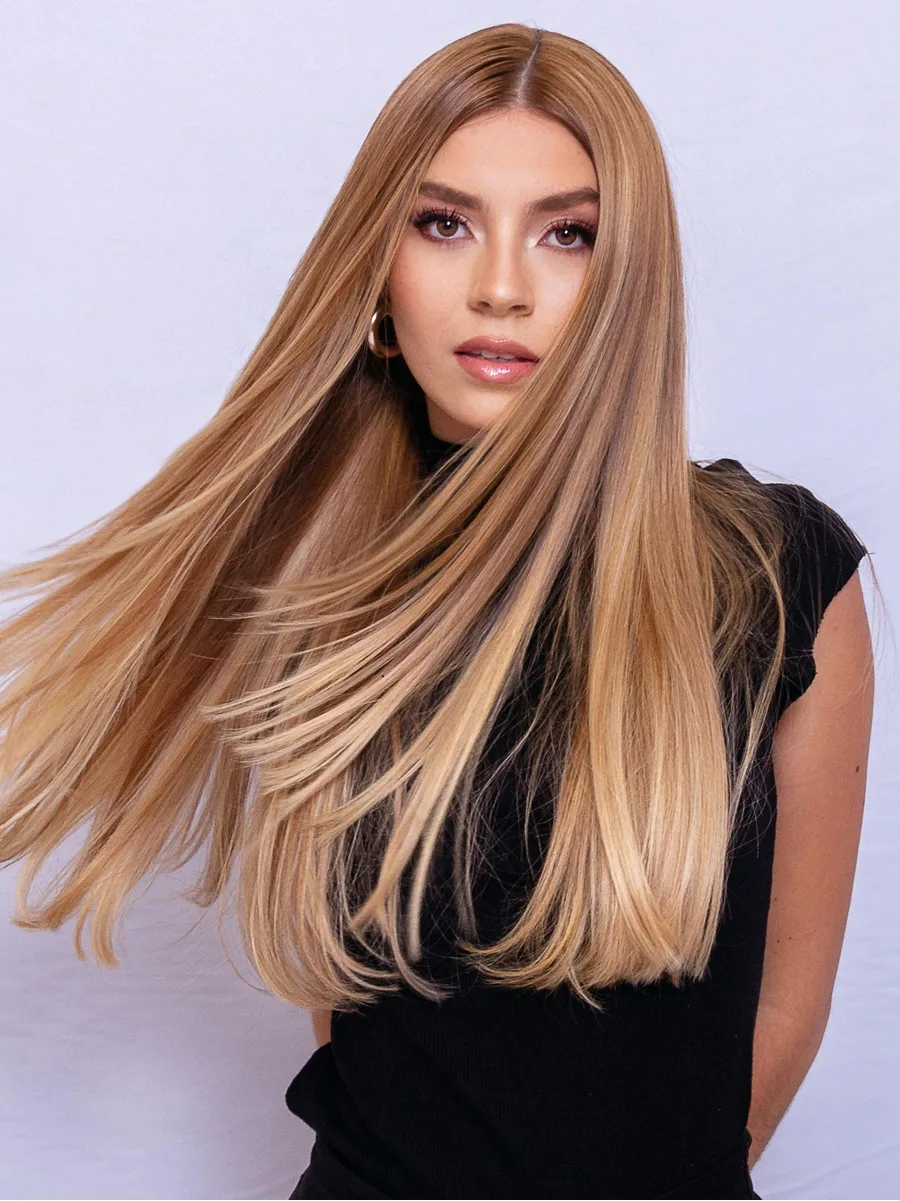 Retrato de estúdio de uma mulher a sacudir o cabelo loiro acaramelado, comprido e brilhante