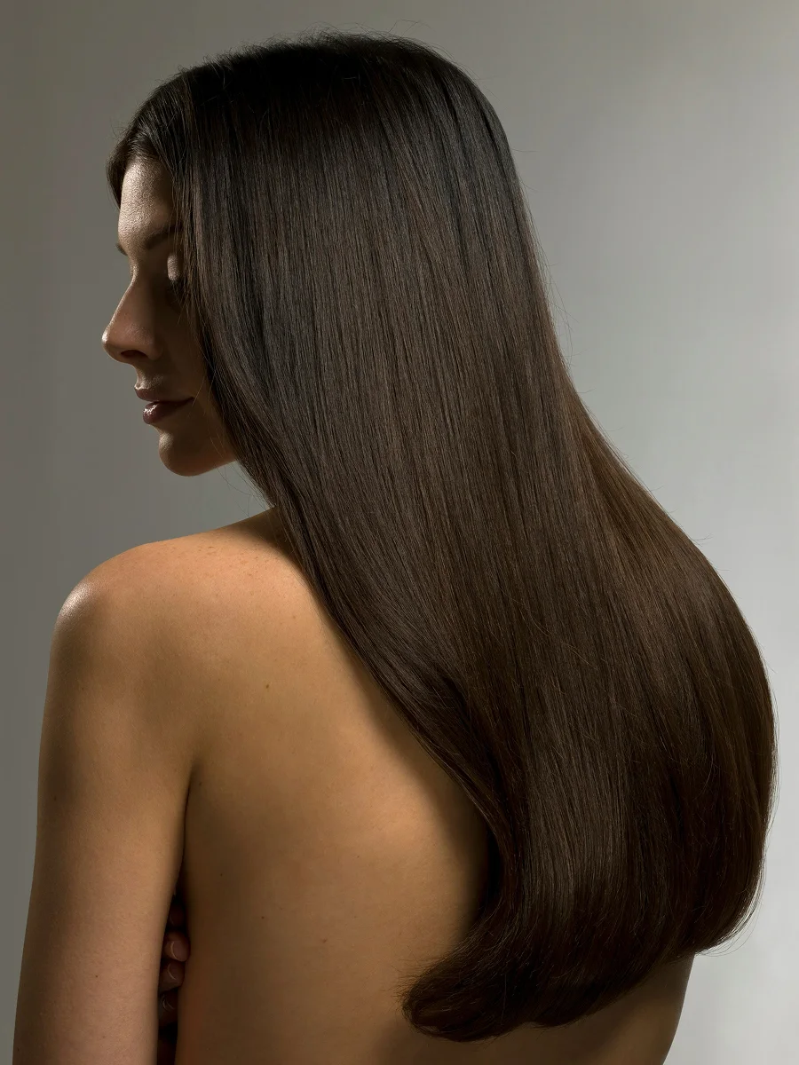 Retrato de estúdio, de perfil, de uma mulher com cabelo castanho, comprido e brilhante