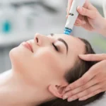 Grande plano de uma mulher relaxada de olhos fechados durante um tratamento HydraFacial num salão tranquilo