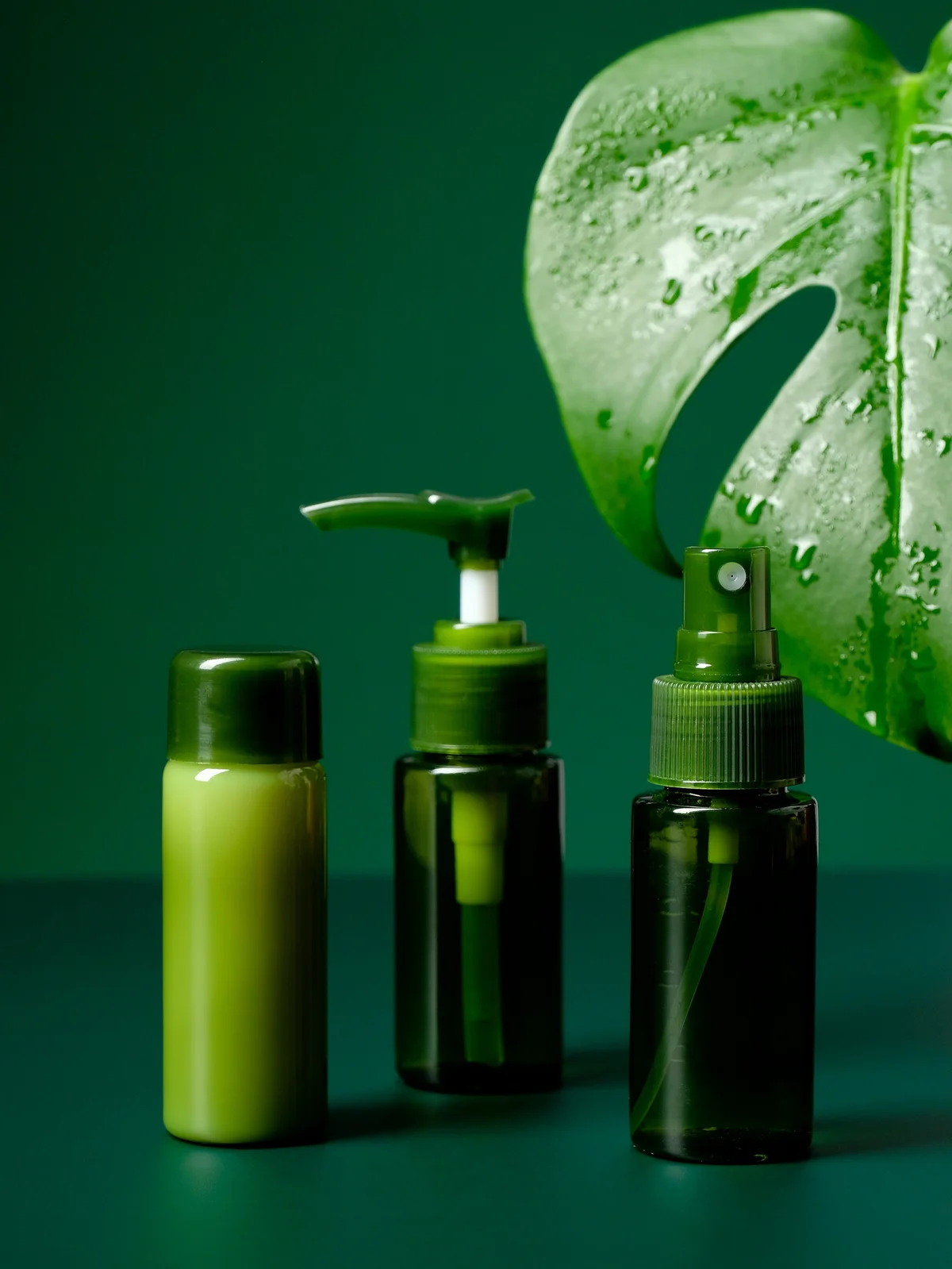 Foto de produto de três géis e cremes calmantes em frascos verdes, com uma grande folha tropical verde ao fundo