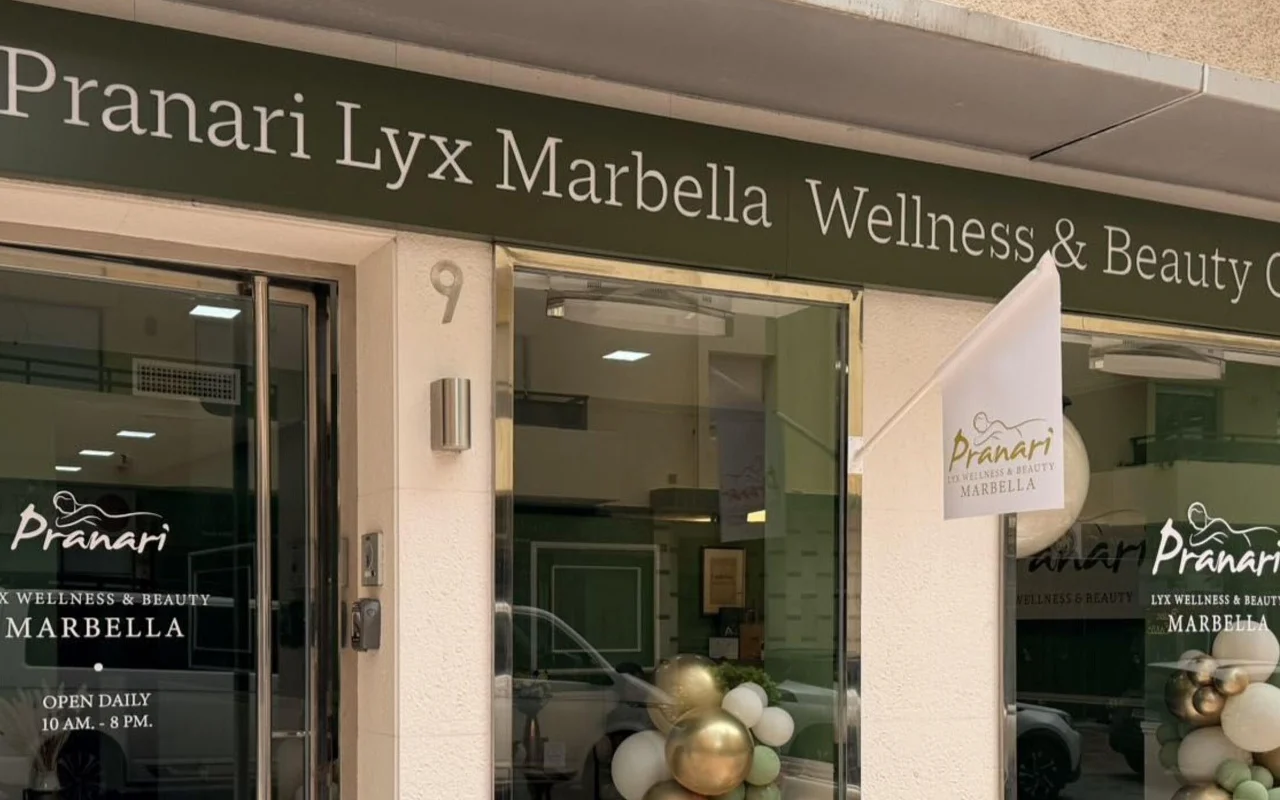 O espaço da Anchan Massage em Marbella, um estúdio de bem-estar e beleza de fachada verde com balões brancos e dourados junto à entrada envidraçada.