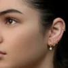 Fotografia de estúdio de uma mulher com uma orelha personalizada, com vários piercings no lóbulo e uma argola na hélice