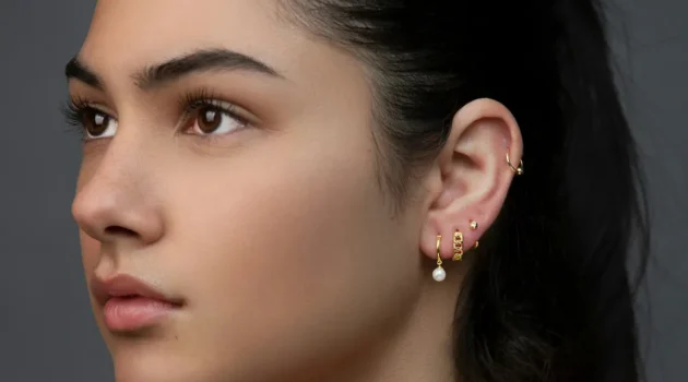 Fotografia de estúdio de uma mulher com uma orelha personalizada, com vários piercings no lóbulo e uma argola na hélice