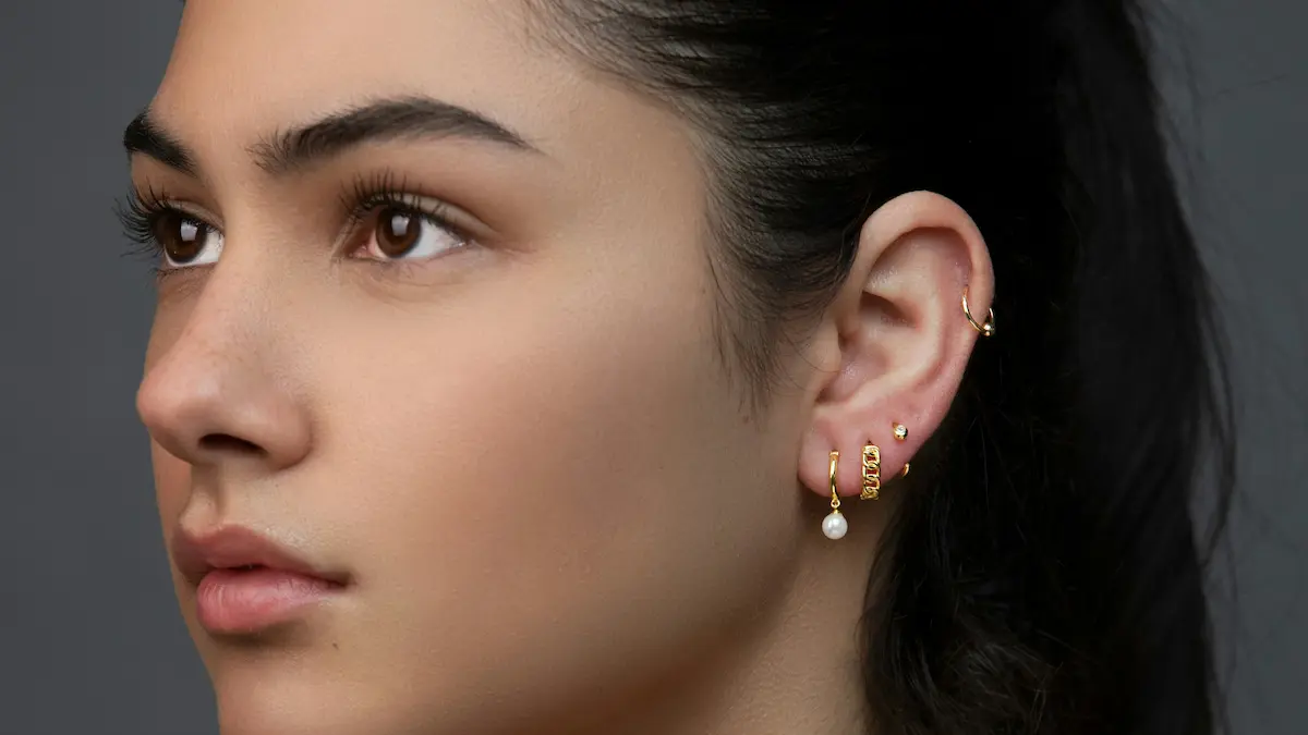 Fotografia de estúdio de uma mulher com uma orelha personalizada, com vários piercings no lóbulo e uma argola na hélice