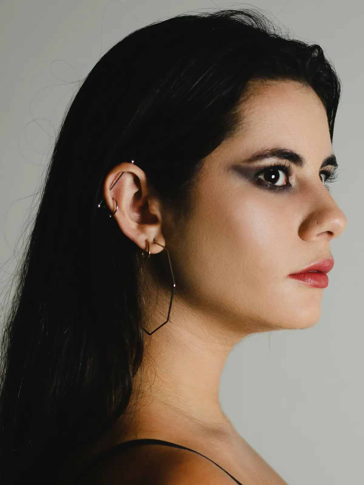 Fotografia de estúdio de uma mulher com um haltere industrial e furos no lóbulo e na hélice