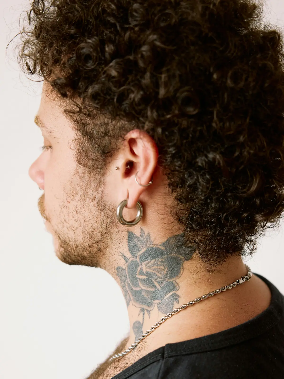 Fotografia de trás de um homem com furos no lóbulo, na hélice e no tragus