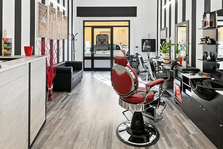 Cadeira de barbeiro vintage vermelha em Hair 99 em Alghero, com as paredes às riscas brancas e pretas características.