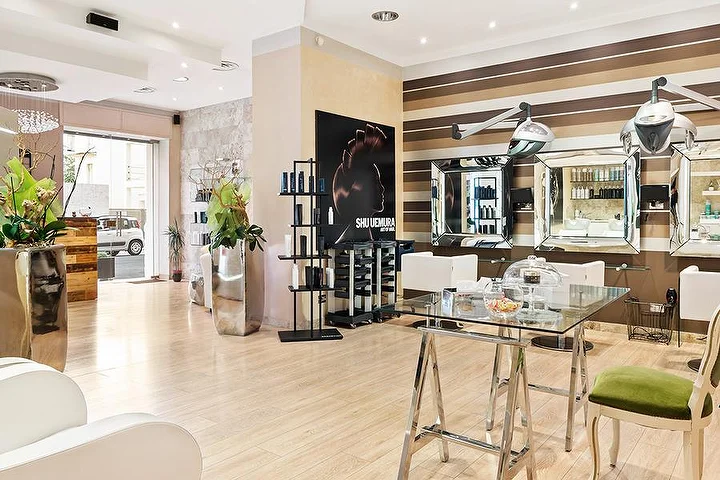 Postos de styling elegantes no salão Hair Queen em Cagliari com paredes às riscas creme e castanhas e altos vasos prateados.