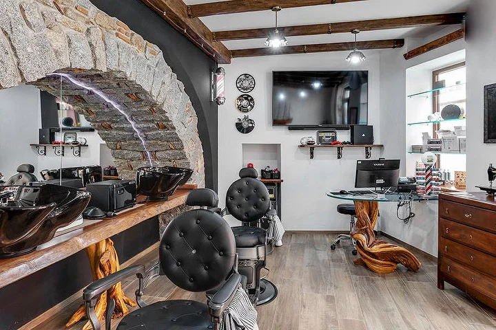 Cadeira de barbeiro rústica junto a um arco de pedra em La Bottega di Pablo, na vila de montanha de Lanusei.
