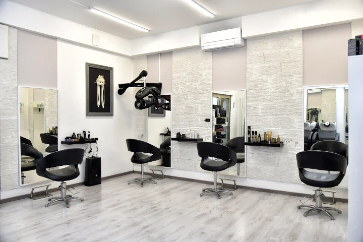 Postos de styling modernos em Sp Beauty di Serena Pinna perto das praias de Pittulongu em Olbia, com cadeiras pretas e grandes espelhos.