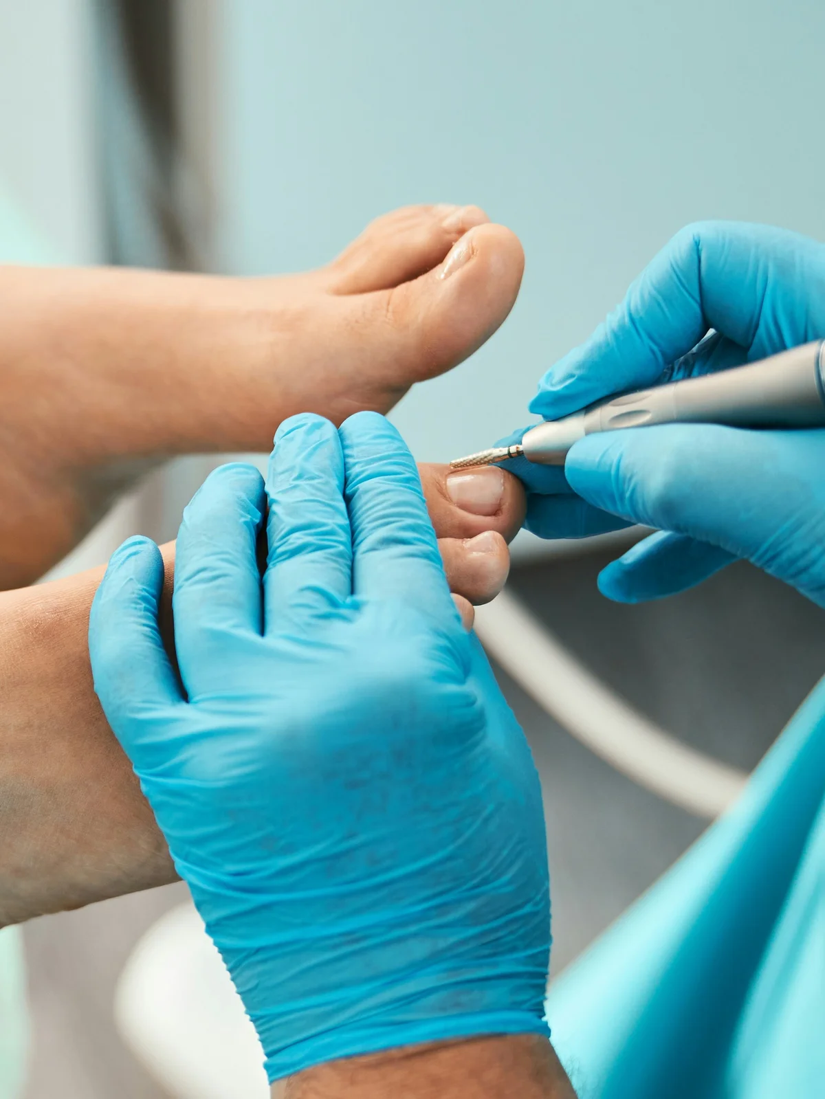 Grande plano de uma esteticista com luva a acertar as cutículas dos dedos do pé de uma cliente com um instrumento pequeno