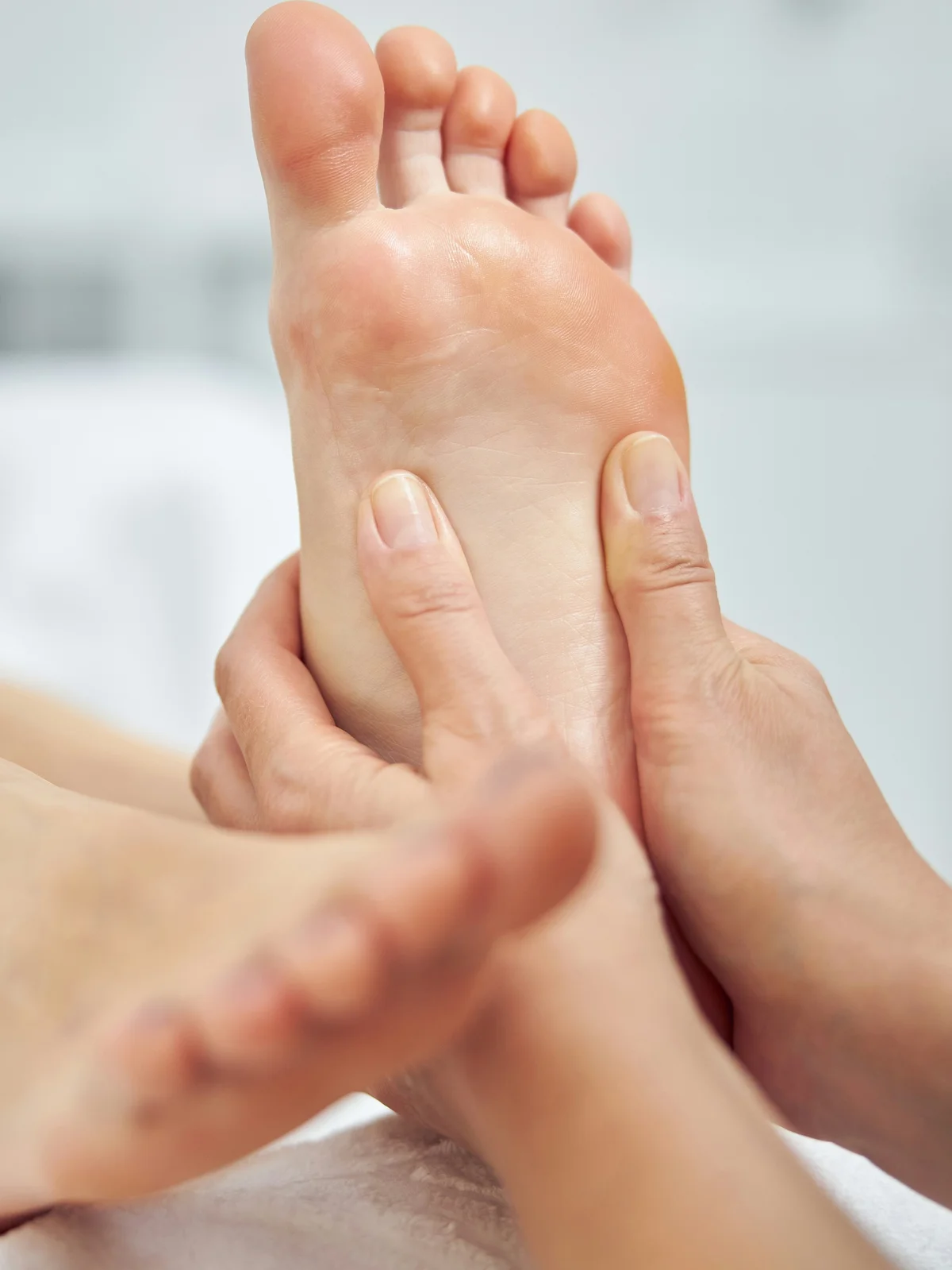 Grande plano de uma esteticista a massajar o pé de uma cliente durante uma pedicure a seco