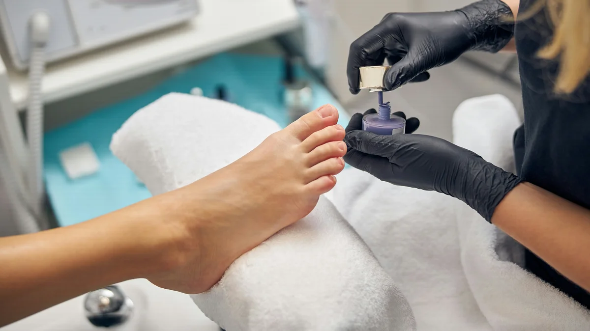 Grande plano de uma manicure profissional a fazer pedicure a uma cliente no salão