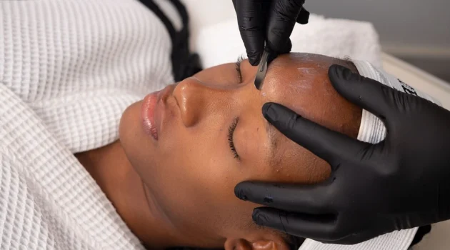 Grande plano de uma esteticista a realizar dermaplaning numa cliente num centro de estética