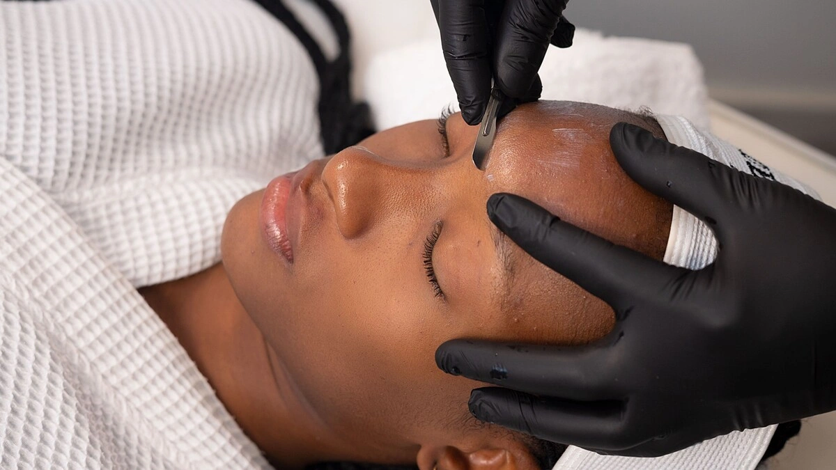 Grande plano de uma esteticista a realizar dermaplaning numa cliente num centro de estética