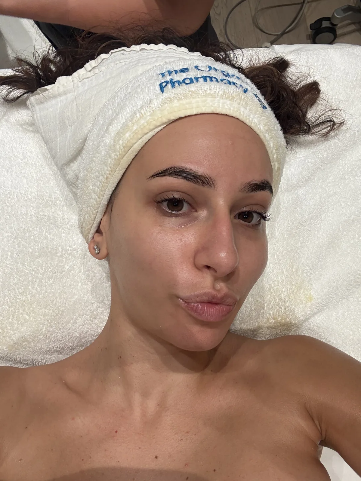 Mulher com pele fresca e luminosa e uma fita no cabelo durante um tratamento facial