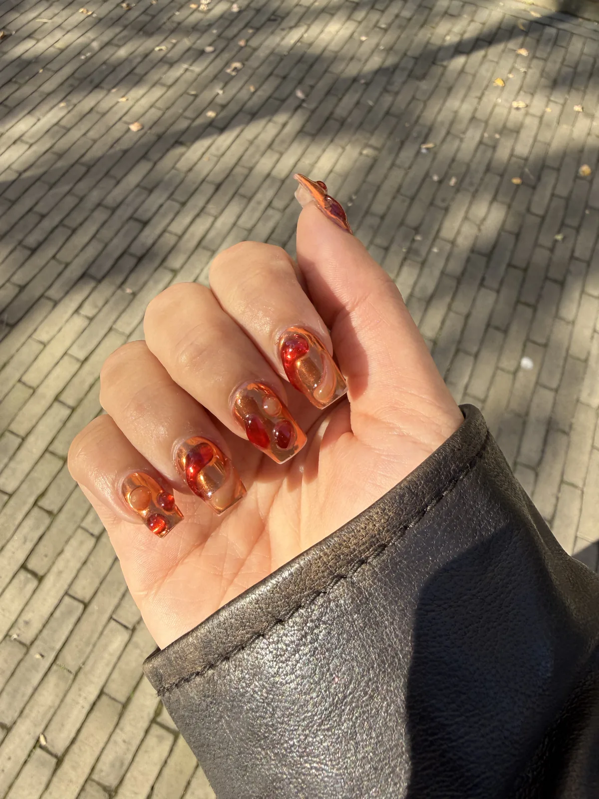 Nail art lava nails com espirais âmbar e vermelhas sobre base transparente