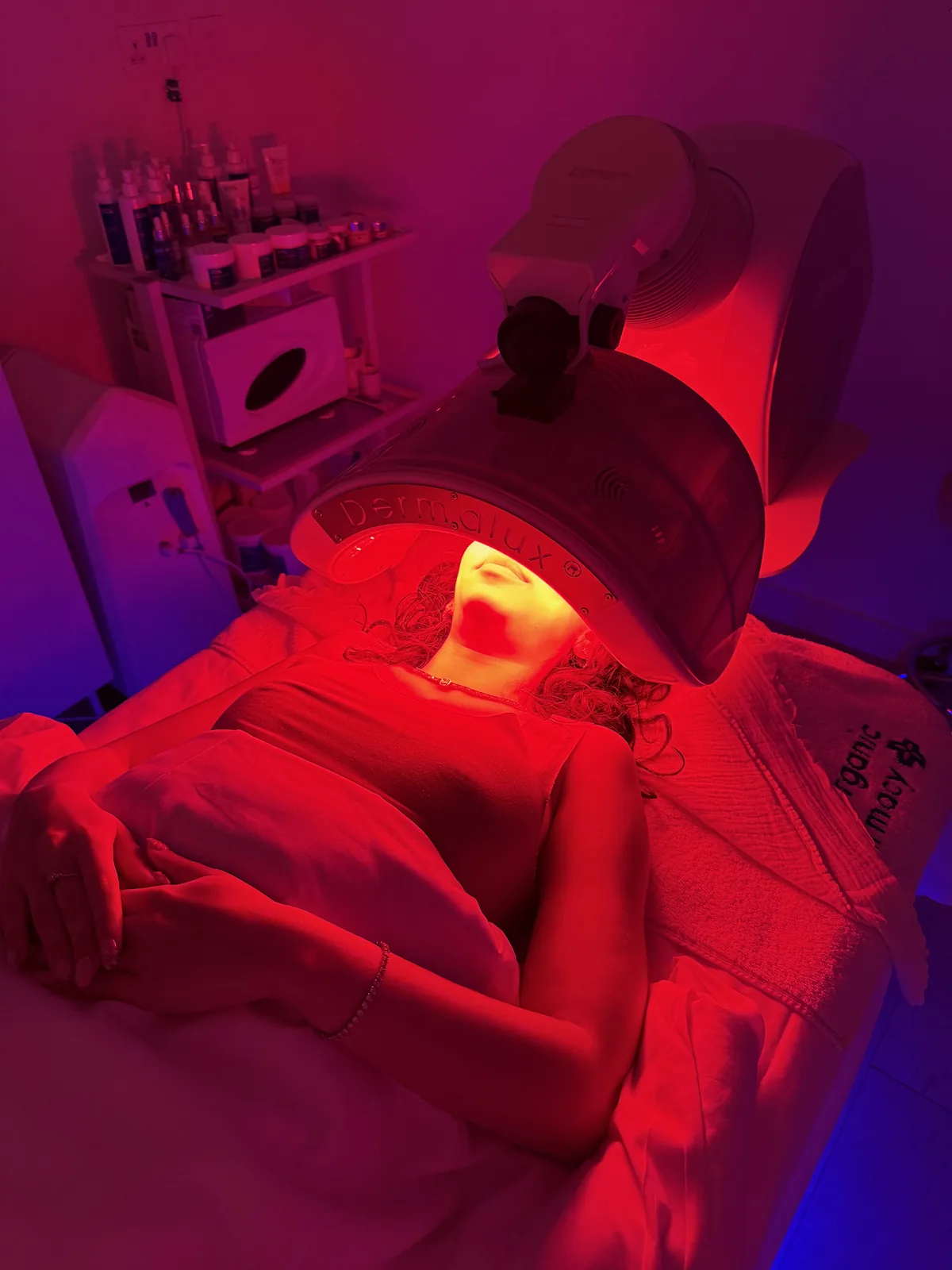Mulher a relaxar debaixo de um painel LED de luz vermelha durante um tratamento de spa